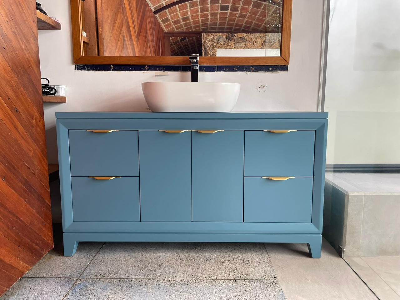 Mueble de baño azul con lavamanos y herrajes dorados