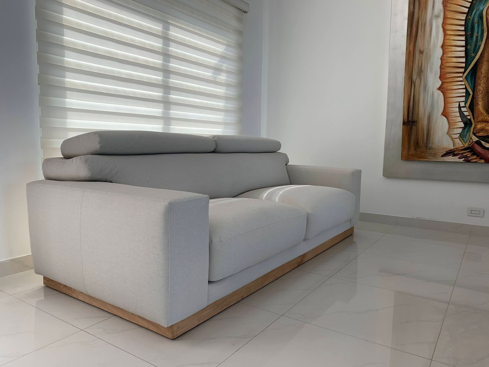 Sofá gris con base en madera en sala iluminada